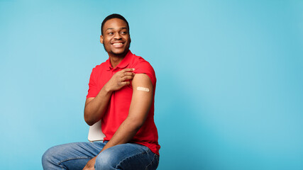 Vaccinated African Guy Showing Arm After Coronavirus Vaccination, Blue Background - obrazy, fototapety, plakaty