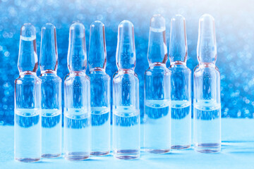Glass medical ampoules on the table on a blue background. Medical glass ampoules.
