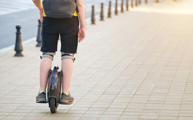 Man on mono wheel in shorts with backpack driving on sidewalk. Boy on electric unicycle. Man rides on monowheel. Guy driving on self balancing transporter with single wheel. Urban electric transport © Tricky Shark