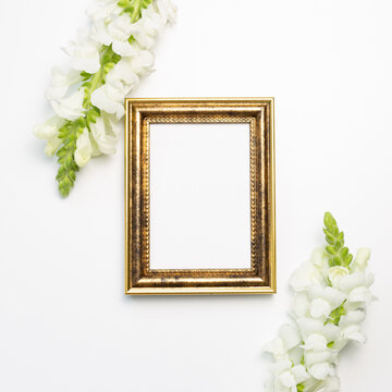 Empty photo frame with snapdragon flowers on white background. flat lay, top view, copy space