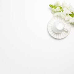 Coffee cup with white snapdragon flowers on white background. flat lay, top view, copy space