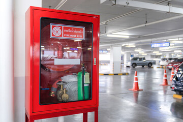 Fire Hose Reel box in the corner of Car Parking., The White Thai Language letter in the middle of...