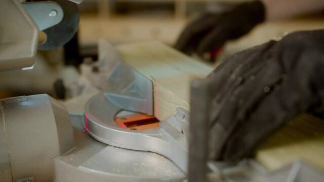 Young carpenter cuts an osb board with a jigsaw. Craftsman's hands in cloth protective gloves. The jigsaw blade cuts precisely.