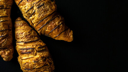 Croissant background. French breakfast croissants, fresh pastry bread with chocolate in bakery on dark stone background. Bread bakery products cafe concept.