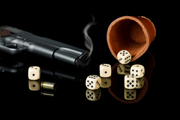 dice and gun with reflection on black background, copy space