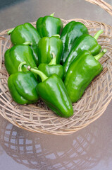 ripe green peppers in wooden basket on glass table