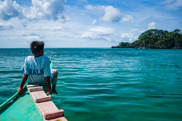 Fototapeta premium A local boy on a boat on the shore of Boracay, Philippines looking out on the horizon.