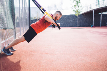 Powerful sportsman training with TRX straps