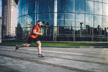 Determined runner running in city near modern building