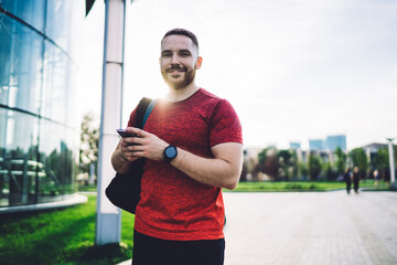 Cheerful man using cellphone on modern street