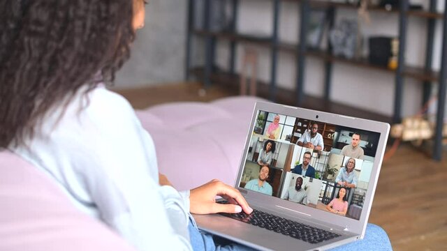 African American female student with afro hairstyle using app for distance video communication, studying online, taking courses while staying at home, looking at laptop screen with group of people