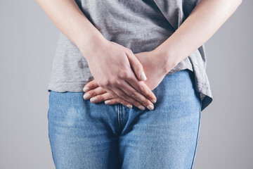 Young woman with painful abdominal pain with hands holding pressing down on her crotch in the lower abdomen.