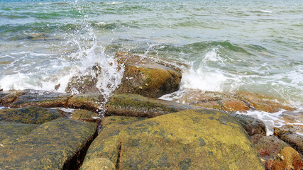 Sea wave with splash water on the rock stone on the beach.
