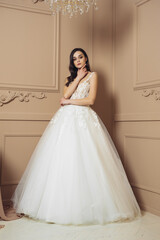 Fototapeta premium Fashion bride in gorgeous wedding dress studio portrait. Beautiful model with bridal makeup and hairstyle in marriage lace dress.