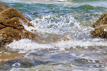 Sea wave with splash water on the rock stone on the beach.