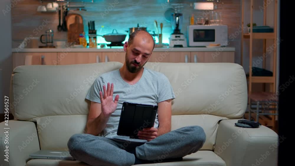 Poster focused man having online meeting videocall on tablet computer speaking using videoconference online