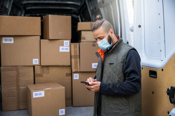 Portrait of a young man shipper with his van during the delivery round in the global pandemic from...