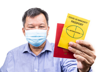 Asian man holding the conceptual Covid-19 Immunity Passport document ready to travel, with focus on documents
