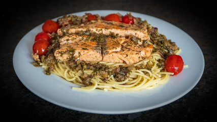 fresh cooking at home and ready to eat - rosted salmon with herbs and cerry tomatoes on spaghetti