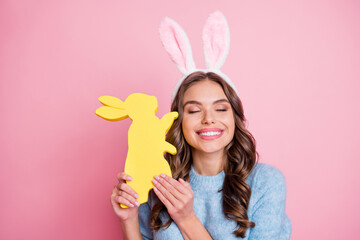 Portrait of attractive cheerful dreamy girl holding easter rabbit enjoying festal mood isolated over pink pastel color background