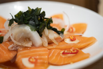 Spicy salmon salad. The plate of thin-sliced salmon with spicy dipping sauce.