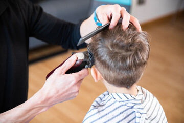 Fototapeta premium A little boy cutting his hair. Hairdresser cutting a child's hair
