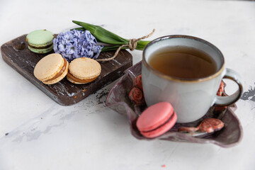 Breakfast tea with macaroons on a wooden background with a hyacinth flower and a beautiful saucer. horizontal orientation