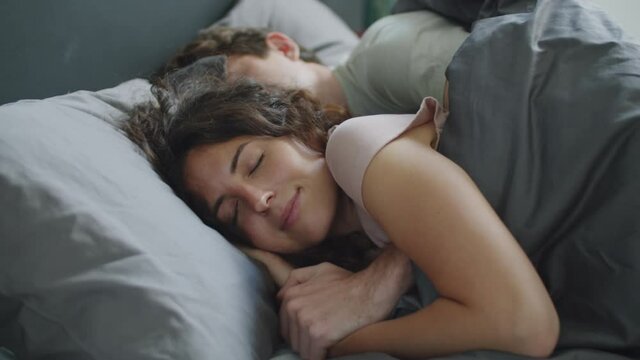 Romantic Caucasian couple embracing and sleeping together on bed in the morning at home