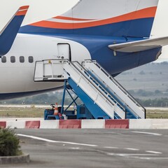 Boarding stairs ramp and back side of colorful airplane. Passenger stair car, aircraft steps next to door of commercial airliner on airport. Modern technology in fast transportation, business flights.