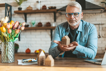 Preservation and restoration of real estate. A mature man holds a model of a house in his hands....