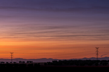 Atardecer en la ciudad con torres eléctricas y las montañas a lo lejos