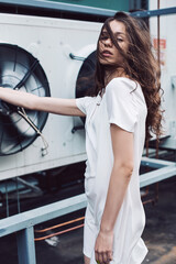 Teenager girl in white dress under fan wind