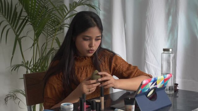 Beautiful woman watching make up tutorial video learning how to do make up. online make up learning concept. Beauty vlogger present beauty cosmetics recording make up tutorial video.