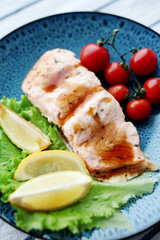Plate with cooked salmon fillet and tomatoes.
