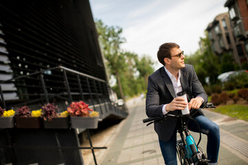 Young businessman on the ebike with takeaway coffee cup