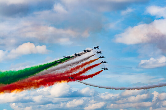teamwork of colorful acrobatic airshow of a team of pilots flying jets on formations with colorful smokes venting from the plane.