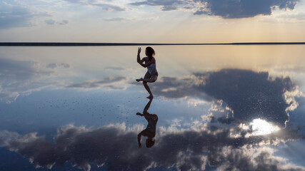 Meditating girl in a calm environment against the backdrop of the sunset in the reflection of the sea.