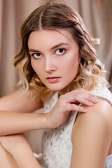 Naklejka premium Portrait of a young woman against a background of white and beige draperies.