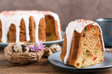 Piece of glazed Easter cake with sprinkles and candied fruits on wooden table, space for text