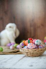 The easter eggs filled in the basket isolated from the rabbit in the background. Easter day.