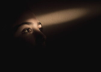 Single ray of light falling over girls eyes