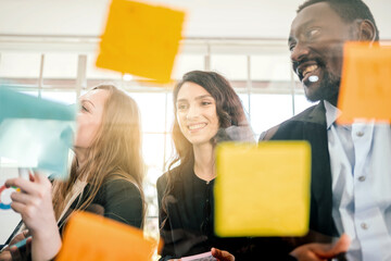 Group of successful business teamwork. Brainstorm meeting with colorful sticky paper note on glass wall for new ideas. Using agile methodology and do business. Brainstorming in a tech start-up office.