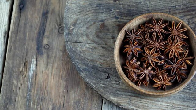 Anise stars in a wooden bowl on the table. Anise aromatic seasoning. Plant seeds. Food and Cooking. Inflorescence in the shape of a star.