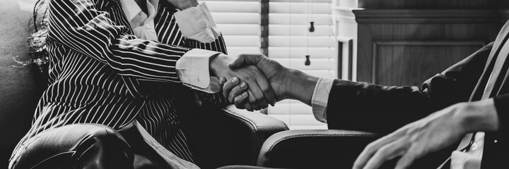 Banner picture of businessman and businesswoman handshaking in office (black and white color)