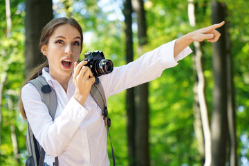 Cheerful woman in the forest takes photos with camera and is enthusiastic about the great motifs