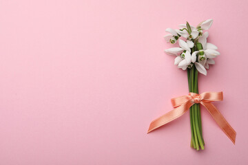Beautiful bouquet of snowdrops on pink background, top view. Space for text