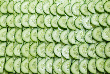 Fresh green slices of cucumber as background.