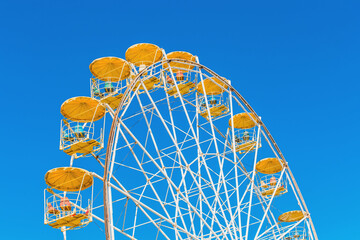 Sightseeing open ferris wheel in the amusement park on blue sky background