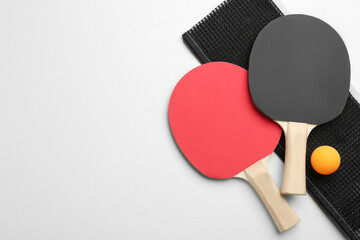 Ping pong rackets, net and ball on white table, flat lay. Space for text
