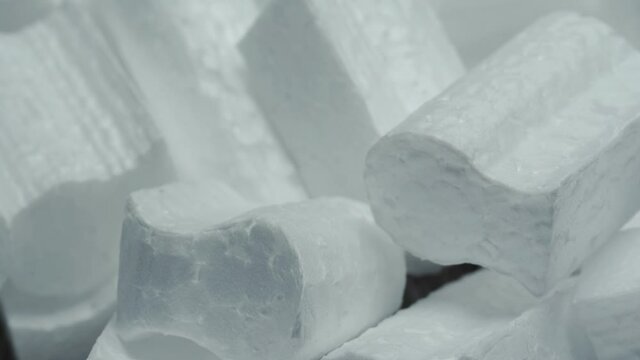 small pieces of white styrofoam close up, top view in motion